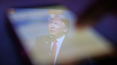 Kiev, Ukrayna - 8 Kasım 2019: akıllı telefon ekranında patronluk taslayan Donald Trump 'ın neşeli görüntüsü. Amerikan izleyicilerini yeni ufuklara götürüyor. Erkek parmak kaydırma metinleri ona empoze edildi