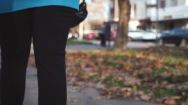 Çanta, sonbaharda parkta bir kadın eli tarafından ağır çekimde sallanıyor. Orijinal arka plan, güneşli bir sonbaharda ağır çekimde, bakımlı bir kadın eli tarafından sallanıyor. İlham verici ve neşeli görünüyor..