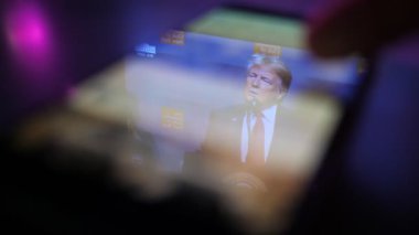 Kiev, Ukrayna - 8 Kasım 2019: Donald Trump 'ın muhteşem manzarası akıllı telefon ekranında. O, Amerikan seyircilerini eğlendiriyor. Erkek parmak kaydırma metinleri ve ona dayatılan fotoğraflar