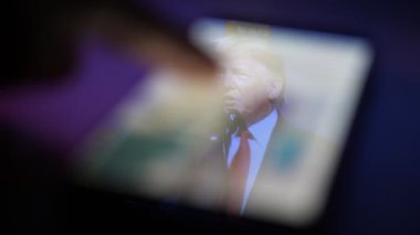 Kiev, Ukrayna - 8 Kasım 2019: Amerikan Başkanı Trump 'ın ilham verici görüntüsü akıllı telefon ekranında. O, Amerikalı seyircilerle konuşuyor. Erkek parmak kaymağını yiyor. Mesajlar ve fotoğraflar ona zorla kabul ettiriliyor.