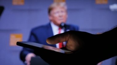 Kiev, Ukrayna - 8 Kasım 2019: Amerikan Başkanı Trump 'ın orijinal konsept görüntüsü bir televizyon ekranına yansıdı. Dünyayı ikna etmeye çalışıyor. Bir erkeğin arka planında akıllı telefonu vardır..   