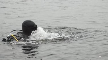 Odessa, Ukrayna - 11 Ekim 2019: Profesyonel siyah takım elbiseli ve maskeli bir yüzücünün yaz aylarında sakin bir nehirde dalgıçla hareket edişinin ve su sıçratışının orijinal görüntüsü.