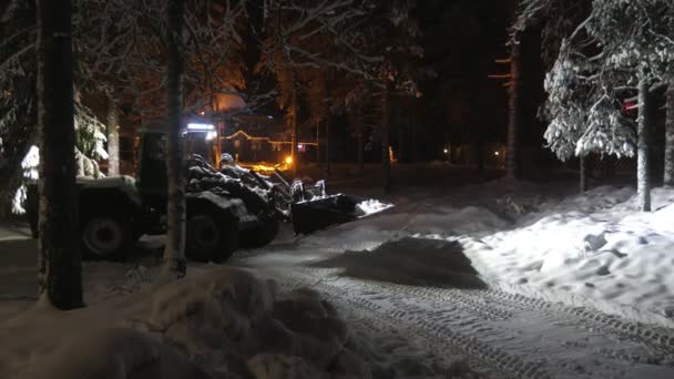 冬の夜にフィンランドで大きなスクープクリーニング森を持つ現代のトラクタースローモーションで夜にフィンランドの松の木と光と大きな炎の移動とクリーニング森と現代のブルドーザーの印象的なビュー — ストック動画