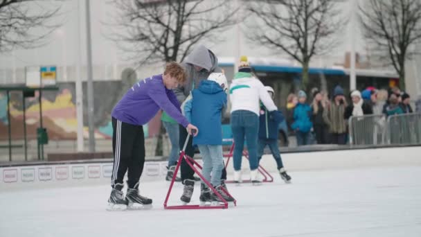 フィンランドのヘルシンキ 2019年12月12日 遅い動きで冬にヘルシンキのアイスリンクのチューブスタンドを使用して 父親と彼の2人の息子から幸せな家族の感情的なビュー — ストック動画