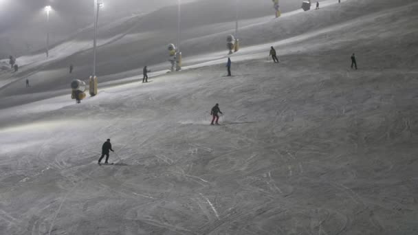 冬にはレヴィスキーリゾートの横断的な方法で下に移動するプロのスキーヤー雪の冬にフィンランドのレヴィスキーリゾートで避けられない方法でスポーツスキーヤーの陽気な眺め 彼らは雪の波を残して — ストック動画