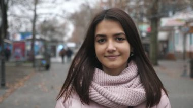 Sonbaharda ağaçlarla dolu bir sokakta ayakta duran ve gülümseyen mutlu esmer kız. Parlak, zeki ve romantik gözlü güzel bir kızın parlak portresi. Uzun, gevşek saçlar.