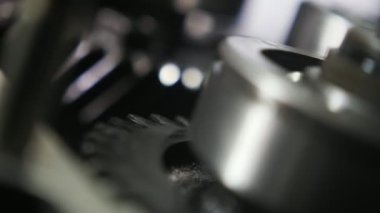 Çağdaş araba aktarımında ince metal bir zincir tarafından hareket ettirilen büyük bir dişli çarkına sabitlenmiş dönen bir topun şaşırtıcı bir şekilde yakın çekimi, parlak bilye ve geniş dişli bir dişli çarkın hızlı sürüşü. Etkileyici görünüyor..