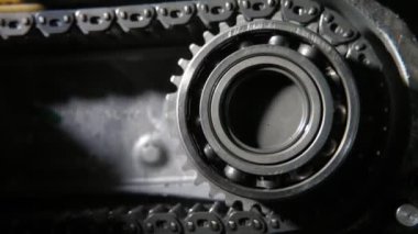 Dönen bilye dişleri olan büyük bir çark taktı ve hareket eden zincir hareket eden bir top tekerleğinin etkileyici bir şekilde kapanması için dişleri metal bir zincir tarafından teknolojik ve ince bir şekilde çekilerek büyük bir dişli çarkına sabitlendi.