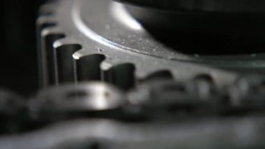 Çağdaş bir otomobil şanzımanında ızgara görünümlü zincir tarafından hareket ettirilen geniş dişli istiridyelerin yakın plan çekimleri ile metal zincirle kenetlenmiş ve vites kutusunda hızla hareket eden geniş dişli dişler. Endüstriyel ve teknolojik görünüyor.
