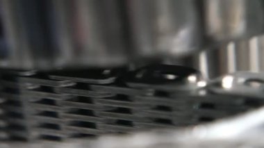 Modern bir araba vites kutusundaki ızgara zincir şeritlerinin üzerinde dönen parlak tekerlekli merdiven geniş bir zincir şerit üzerinde dönen yuvarlak bir silindirin görkemli görüntüsü çağdaş bir otomobil iletiminde ızgara gibi görünüyor. Teknolojik ve neşeli görünüyor..