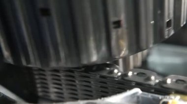 Çağdaş bir otomobil aktarımında geniş bir zincir şeridi üzerinde dönen büyük bir paten, geniş bir zincir şerit üzerinde dönen büyük bir paten teknolojisi ile modern bir otomobil transmisyonunda sayısız delikler. Sert ve iyi görünüyor..