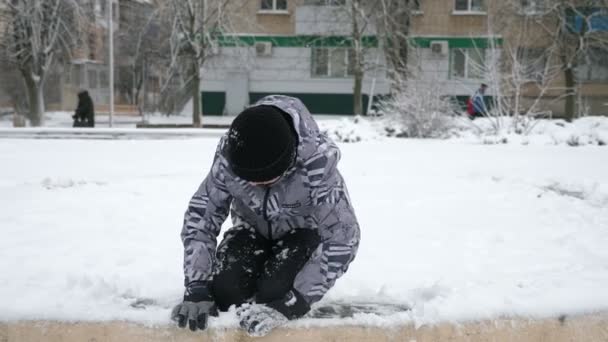 Взволнованный Мальчик Сидящий Снежной Лужайке Играющий Снегом Зимой Сло Веселый — стоковое видео
