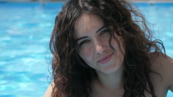 머리에 비키니를 비키니를 날씨에 수영장 가장자리에 여성은 미소를 — 비디오