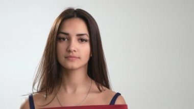 Kırmızı elbiseli neşeli bir kız, beyaz bir stüdyoda ayakta, gülümsüyor ve gülüyor. Beyaz bir stüdyoda gülümsüyor, gülümsüyor ve gülümsüyor. Uzun sarı saçlı, şık kırmızı elbiseli, uzun boylu esmer bir kız..