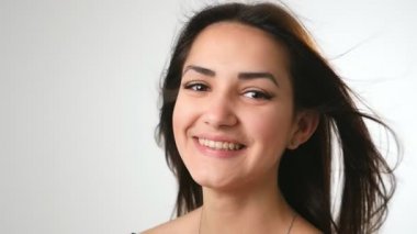 Uzun saçlarını sallayan, neşeli bir şekilde stüdyoda gülümseyen, uzun, bol saçlı, parlak gözlü ve beyaz bir stüdyoda ağır çekimde gülümseyen esmer bir kızın neşeli portresi..