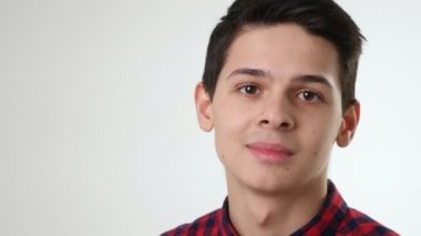 Kareli gömlek giymiş neşeli esmer adam beyaz stüdyo manzaralı beyaz bir stüdyoda oturuyor ve gülümsüyor. Kısa saçlı, kısa saçlı, kareli bir adam beyaz bir stüdyoda oturuyor ve gülümsüyor. İronik, mutlu ve iyi görünüyor..
