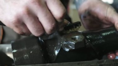 Çalışanların elleri, atölyedeki fırçayla etkin bir şekilde metalik bir araba temizleme işini hallediyor. Küçük atölyede küçük bir fırçayla işçilerin ellerini temizliyor ve büyük bir metalik oto detayını ovuyor. O, hevesle aktif olarak çalışır.. 