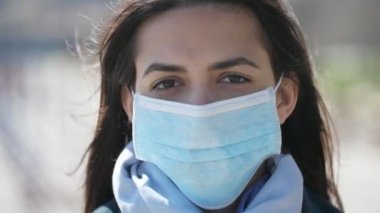 İlkbaharda hijyenik bir maske takmış esmer bir kadın. Rüzgarlı havada sallanan güzel esmer kız portresi. İlkbaharda Dnipro rıhtımında Coronavirus 'a karşı hijyenik maske takıyor.