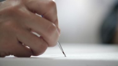 Genç bir sanatçının el resmi, beyaz bir gazetede uzun mavi bir fırçayla büyük bir stüdyoda, beyaz bir kağıtta uzun mavi püsküllü bir resim oluşturan genç bir sanatçının etkileyici bir yakın çekimi. Güzel ve havalı fırça darbeleri koyuyor..