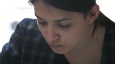 Aristokrat kız stüdyoda büyük beyaz bir çarşafa oturup resim çiziyor. İnce hatları olan güzel esmer bir kız stüdyoda büyük beyaz bir gazetede dar mavi püsküllü bir resim çiziyor.