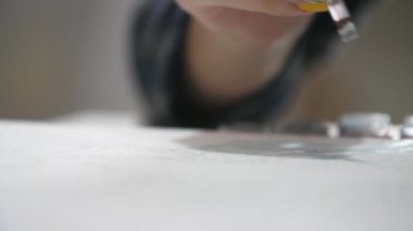 Sarı ve mavi makyajlı kadın ressam elleri sarı ve mavi makyajlı kadın elleri ve havadar bir stüdyoda beyaz bir tuvale estetik yağlı boya darbeleri yerleştiren uzun bir fırça.