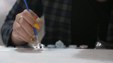 Ukraynalı kadın ressam, vatansever makyajlı, kağıt bir çarşafa resim çiziyor. Sarı makyajlı, elinde mavi bir fırça olan çekici bir esmer kızın, stüdyodaki beyaz kağıt bir çarşafa yağlı boya darbeleri uygulamasını ilham veriyor.