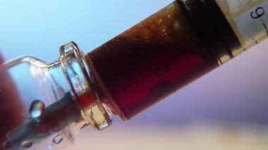 Laboratuvarda Coronavirus 'u test etmek için bir şırıngadan cam bir şişeye kırmızı kan enjekte edildi. Cam bir şişeye yerleştirilen plastik şırınganın yakın çekimi heyecan vericiydi. Günümüz klinik laboratuvarında Coronavirus' u test etmek için kırmızı kan enjekte edildi.