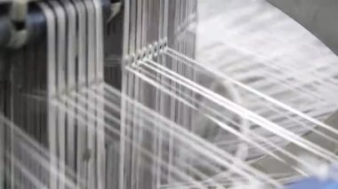 Plastik tarım dokusu için birçok beyaz kablo titreşiyor ve örgü örüyor. Metalik makineler ve özel tarım çuvalları ve modern bir bitki için plastik branda ören birçok beyaz telin neşeli yakın çekimi..