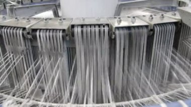 Yüksek sütunlu, dalgalı plastik iplere bağlı metal makineler. Yüksek konik sütunlara bağlı küresel metal makinelerin neşeli görüntüsü. Bitkilerdeki tarımsal çuvallar için plastik branda yapıyorlar.
