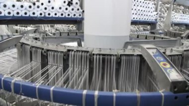 Tarım fabrikasında dönen ve büyük plastik dokular ören beyaz konik sütun örgü ipleri ve birçok metalik iğnelerle ayaklanan büyük bir sütunun görkemli görüntüsü tarım bitkisindeki plastik poşetlerin üretimi için büyük beyaz bir tuval oluşturuyor.