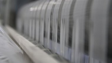 Naylon torbalar üreten büyük makinelerin beyaz telleri büyük bir tarımsal fabrika atölyesinde tarımsal ihtiyaçlar için plastik torbalar üreten büyük metal makinelerde hareket eden beyaz iplerin görüntüsünü heyecanlandırıyor..