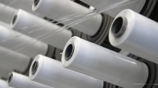 Longues rangées de bobines blanches révoltantes avec de minces cordes qui s'enroulent lentement sur elles Vue splendide de nombreuses bobines blanches qui se déplacent et enroulent des cordes blanches sur elles pour faire de grands sacs en plastique blanc pour l'agriculture sur une usine agricole contemporaine .