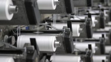 Düzinelerce beyaz makaralı plastik torbalar modern bir tarım fabrikasında plastik torbalar yapıyorlar. Düz beyaz bobinlerin etrafındaki düz çizgilerin harika manzarası ve dalgalı çubuklar modern bir fabrikada tarım için plastik torbalar yapıyorlar..