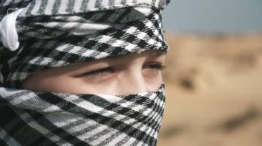 Güneşli bir günde, sınırsız bir çölde dikilen cesur bir çocuk, güneşli bir baharda, siyah beyaz bir kufiye giymiş cesur bir çocuğun, güneşli bir çölde dikilip bir kenara bakarken dörtte üçünü hayrete düşürüyor. Gergin hissediyor..