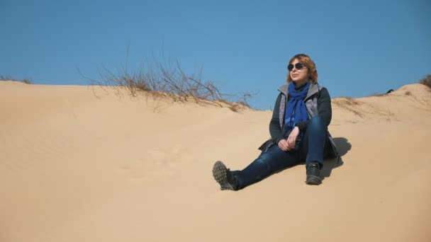 사막을 여행하는 여행자가 사막에 선글라스 청바지 스카프를 사막에 미소짓는 금발의 — 비디오