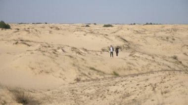 Yanan güneş ve iki yorgun genç insan, kumlu çölde ağır çekimde hareket ediyorlar. Sırt çantalarıyla gezen, kumlu çöllerde gezen yorgun çiftleri hayret verici bir şekilde görüyorlar. Ve bahar aylarında güneşin altında ağır çekimde heyecan verici duygular arıyorlar..