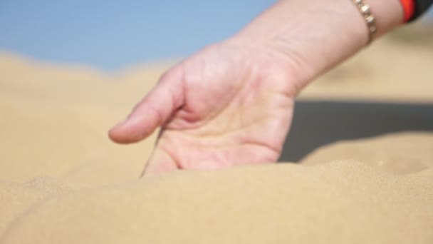 在春天的一个阳光明媚的日子里 男孩的手在沙漠里抓起干沙 用手指把它筛下来 看到年轻的男孩的手在干沙里打滚 然后把它抬起来 通过张开的手指在沙漠里把它筛起来 — 图库视频影像