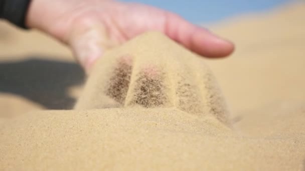 乾燥した砂の中に浸透し それを取り上げ スローモーションで春の晴れた日にスプレッド指を介してふるいにかける若い男性の手の素晴らしい景色 — ストック動画
