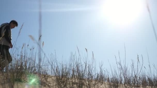 輝く太陽と2人の疲れた若い旅行者が雪の中の砂の砂漠でプルード Moで疲れたカップルの若い観光客の感情的なビューバックパックは春の雪の中で燃える太陽の下でゆっくりと旅し 砂の砂漠を移動する — ストック動画