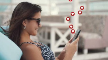    Bikini ve güneş gözlüklü şık bir kızın deniz kenarında şezlongda oturması ve sosyal ağlardan pek çok beğeni toplaması. Kullanıcı arayüzü canlandırması