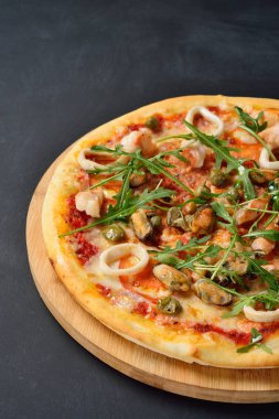 Deniz ürünleri kara kaplı tahta üzerinde pizza