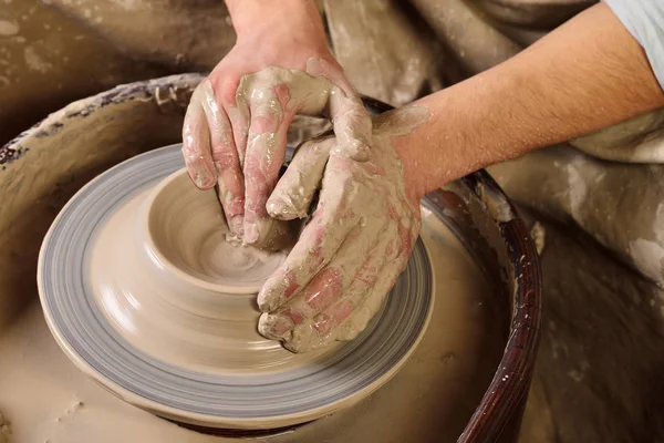 Creating a jar or vase. Master crock. Man hands making clay jug.