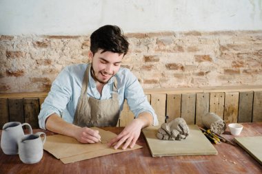 gülümseyen yakışıklı genç Meksikalı potter ceram çizimler yapar