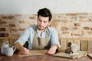 yakışıklı genç Meksikalı potter seramik p çizimler yapar
