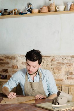 yakışıklı genç Meksikalı potter seramik kağıt üzerinde çizimler yapar. el işi, küçük işletme, hobi iş kavramı. 