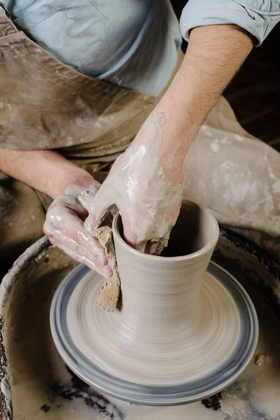 Çömlekçilik, atölye çalışması, seramik sanat konsepti - erkek ellerine yakın çekim aletleri ve suyla yeni aletler yontuyor, insanın parmakları çömlekçi çarkı ve çiğ çilingirle çalışıyor, ön görüş