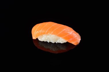 Yansıması ile siyah arka plan üzerine somon suşi nigiri. Ja