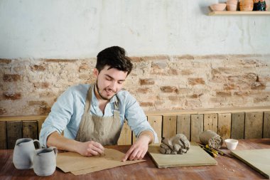 gülümseyen yakışıklı genç Meksikalı potter seramik kağıt üzerinde çizimler yapar. el işi, küçük işletme, hobi iş kavramı. 