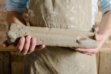 Potter, araçlar, Seramik Sanat kavramı - sakallı bir önlük giymiş esmer erkek gülümseyen genç efendi şamot, bir Fransız Atölyesi'nde hammadde ile büyük parçalarını tutan eller