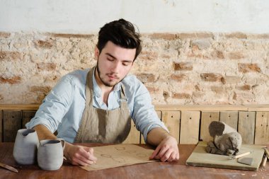 yakışıklı genç Meksikalı potter seramik kağıt üzerinde çizimler yapar. el işi, küçük işletme, hobi iş kavramı. 